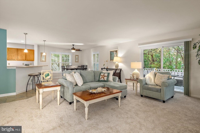 living room featuring baseboards, ceiling fan, and light colored carpet