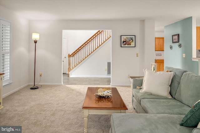 carpeted living room with stairs, baseboards, and visible vents