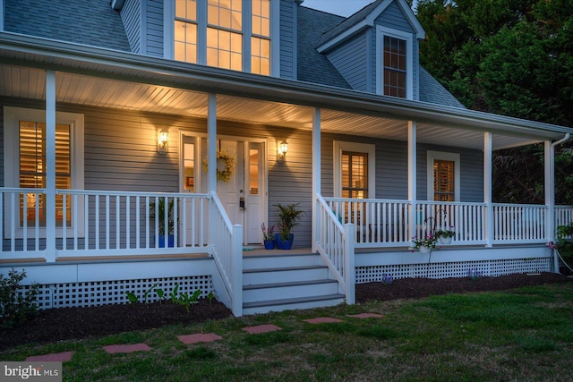doorway to property featuring a porch and roof with shingles