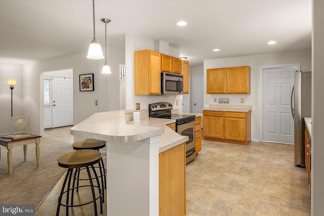 kitchen with light countertops, stainless steel appliances, recessed lighting, a peninsula, and a kitchen bar