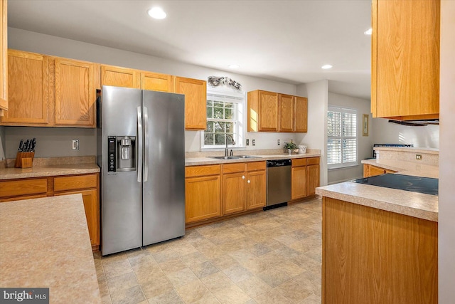 kitchen with a sink, appliances with stainless steel finishes, a healthy amount of sunlight, and light countertops