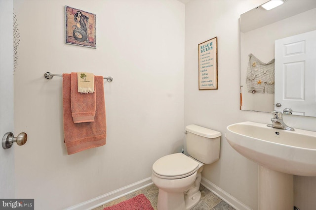 half bathroom with baseboards, a sink, tile patterned flooring, and toilet