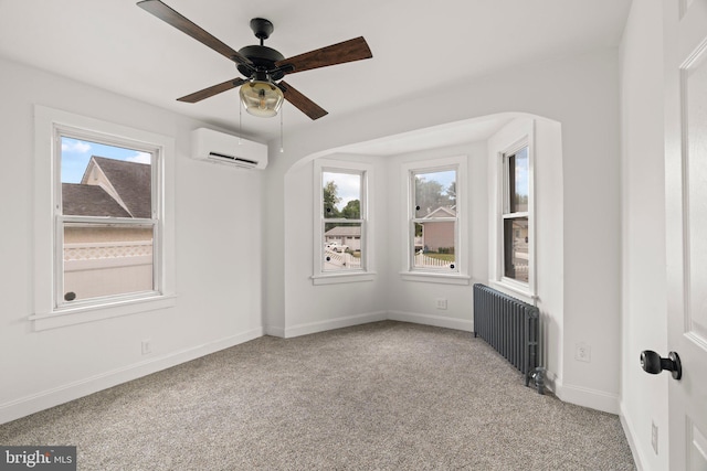 carpeted spare room featuring radiator, a wall unit AC, a ceiling fan, and baseboards