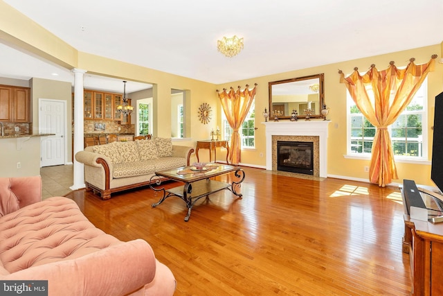 9743 Wyndham Dr, Frederick, MD 21704 - living area with a fireplace with flush hearth, a chandelier, light wood-style floors, decorative columns, and baseboards