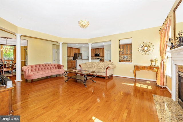 9743 Wyndham Dr, Frederick, MD 21704 - living area with ornate columns, light wood-style flooring, a fireplace, and baseboards