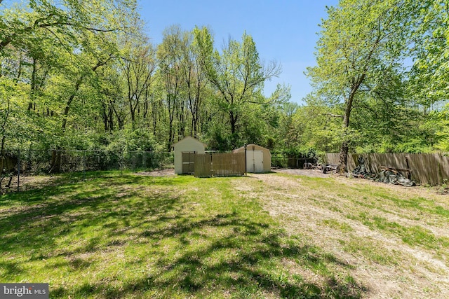 view of yard with a fenced backyard, a storage unit, and an outbuilding
