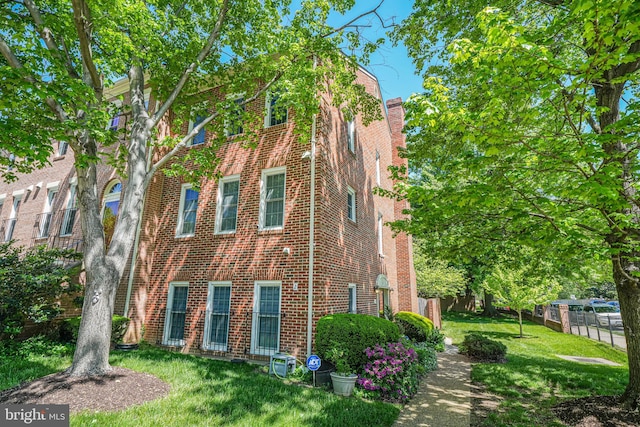 view of property exterior featuring brick siding, a lawn, and a chimney