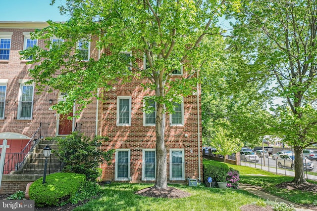 townhome / multi-family property featuring brick siding, fence, and a front yard