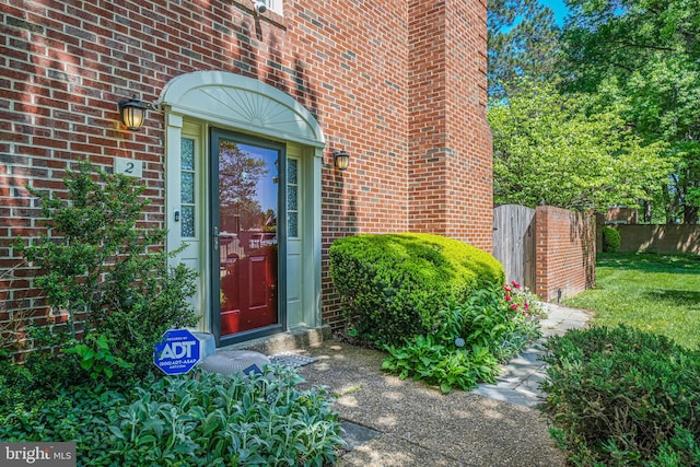 doorway to property featuring fence and brick siding