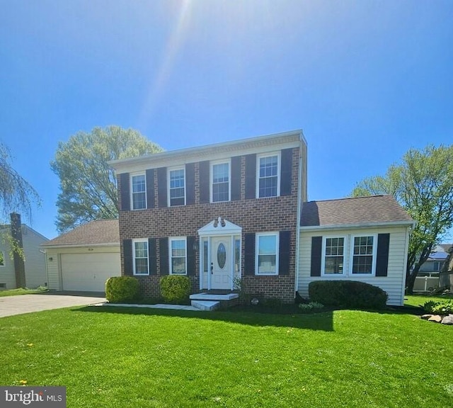 colonial inspired home featuring an attached garage, concrete driveway, brick siding, and a front yard