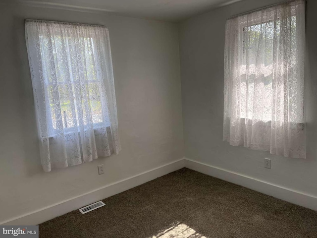 carpeted spare room featuring baseboards and visible vents