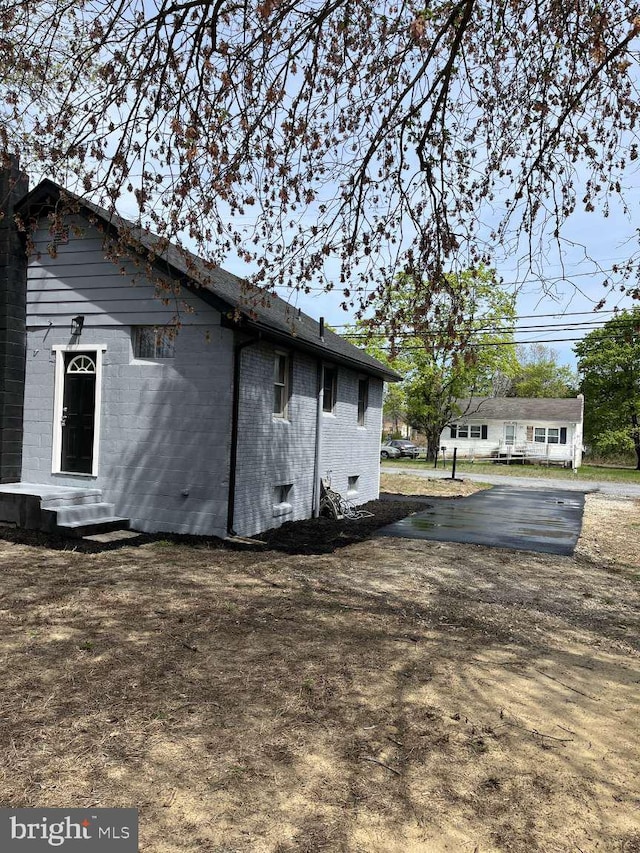 view of side of home featuring brick siding and entry steps