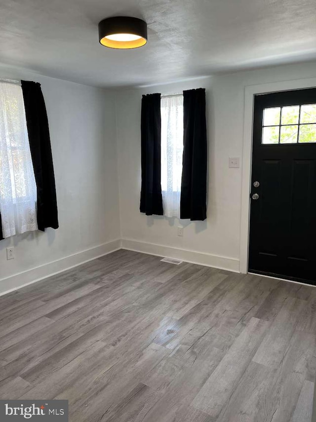 foyer with baseboards, wood finished floors, and visible vents