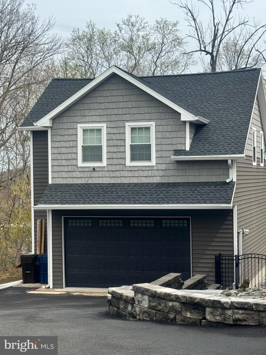 exterior space with a garage and roof with shingles