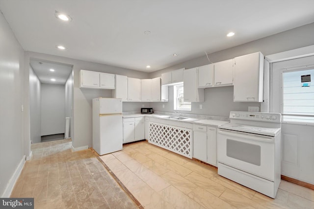 kitchen featuring white cabinets, a sink, white appliances, light countertops, and recessed lighting