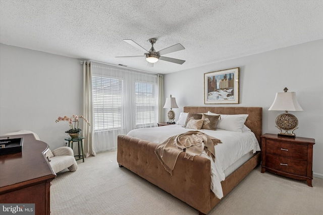 bedroom featuring ceiling fan, light carpet, and a textured ceiling