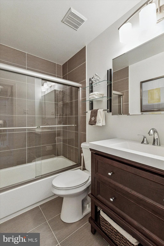 bathroom featuring visible vents, tile patterned flooring, vanity, toilet, and combined bath / shower with glass door