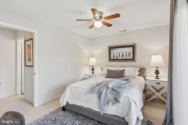 bedroom with baseboards, light carpet, a ceiling fan, and visible vents