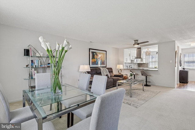 dining room with light colored carpet, a textured ceiling, ceiling fan, and baseboards