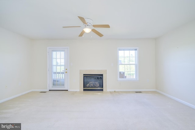 unfurnished living room with carpet floors, a ceiling fan, baseboards, and a fireplace