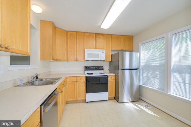 kitchen featuring visible vents, appliances with stainless steel finishes, light brown cabinetry, light countertops, and a sink