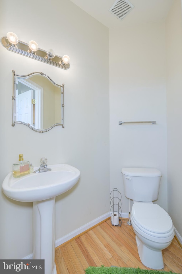 bathroom featuring visible vents, wood finished floors, a sink, baseboards, and toilet