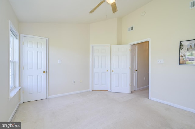 unfurnished bedroom with high vaulted ceiling, baseboards, light colored carpet, and visible vents