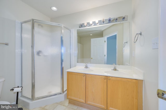 bathroom with double vanity, toilet, a shower stall, and a sink