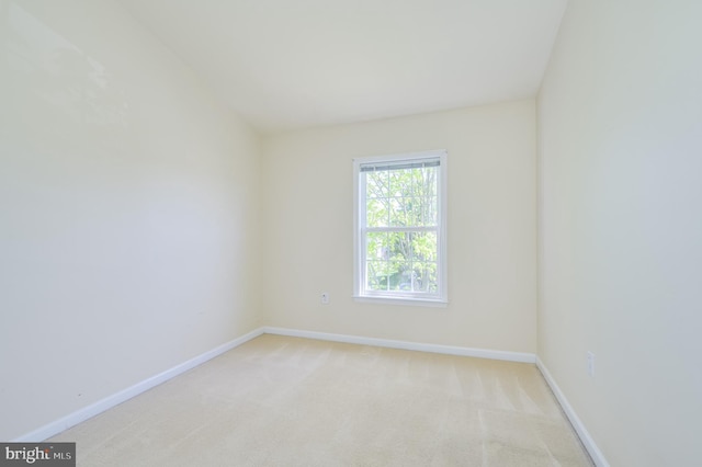 spare room with baseboards and light colored carpet