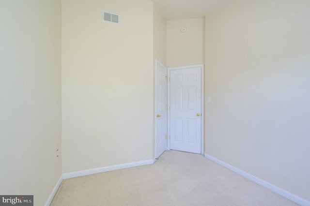 spare room featuring baseboards, visible vents, and light carpet