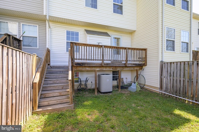 rear view of house with fence, central AC, a wooden deck, stairway, and a lawn