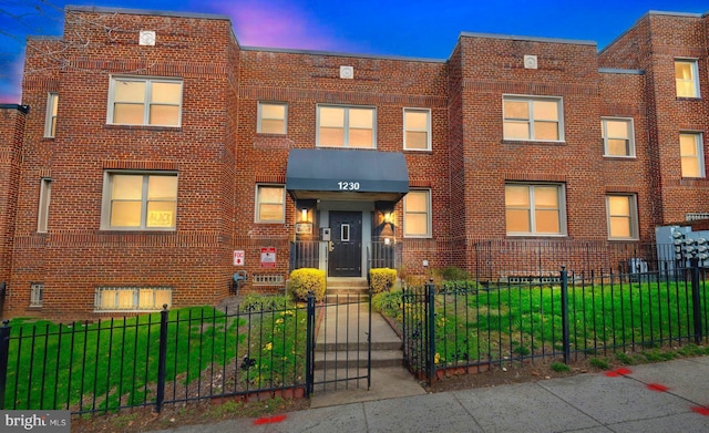 view of front of house featuring a lawn, brick siding, and a fenced front yard