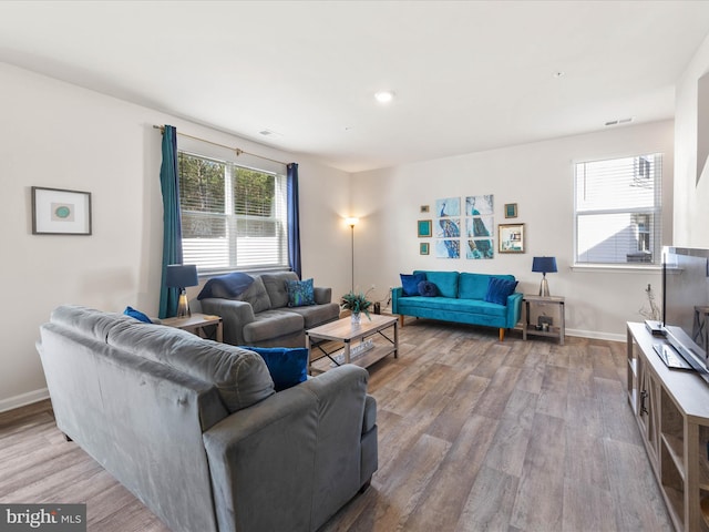 living room featuring baseboards, visible vents, and wood finished floors