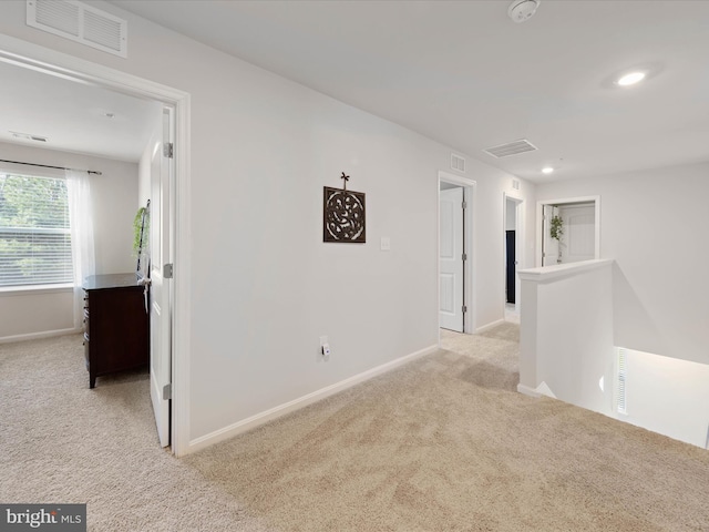 empty room with visible vents, baseboards, and light carpet