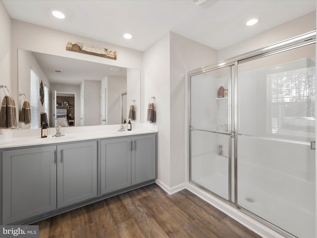full bath featuring double vanity, a stall shower, a sink, and wood finished floors