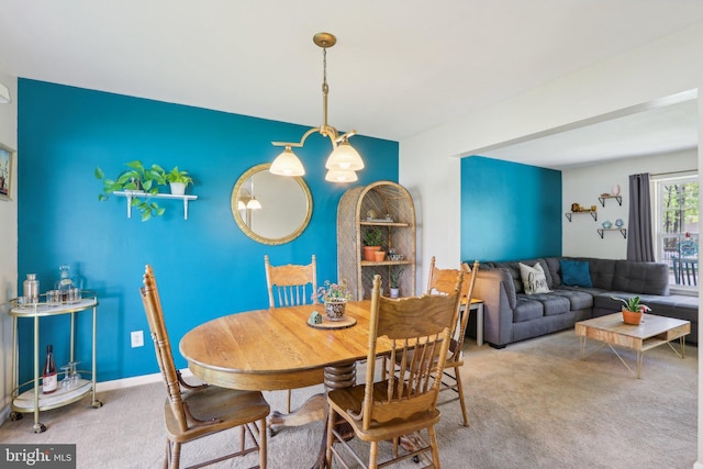 carpeted dining room featuring an inviting chandelier