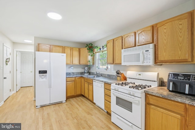kitchen featuring light wood-style flooring, a sink, and white appliances