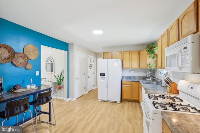 kitchen featuring baseboards, white appliances, light wood-type flooring, and a sink