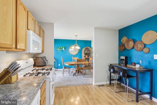 kitchen with white appliances, light brown cabinetry, baseboards, and light wood-style floors