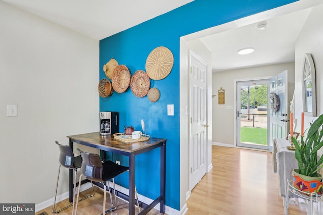 interior space with wood finished floors, baseboards, and an accent wall