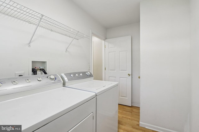 clothes washing area with laundry area, light wood-style flooring, baseboards, and independent washer and dryer