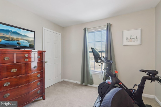 exercise room with baseboards and light carpet