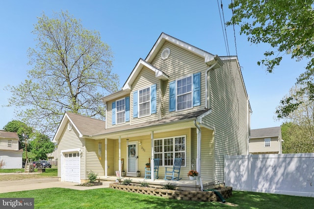 traditional home with covered porch, a garage, fence, concrete driveway, and a front yard