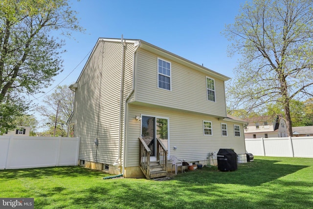 rear view of house with a lawn, entry steps, and fence