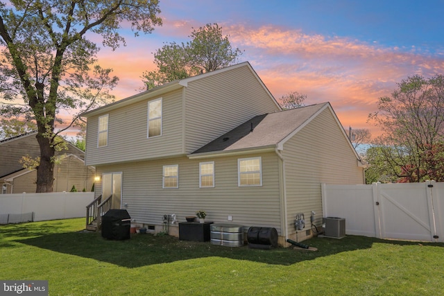 rear view of property with a yard, central AC unit, entry steps, a fenced backyard, and a gate