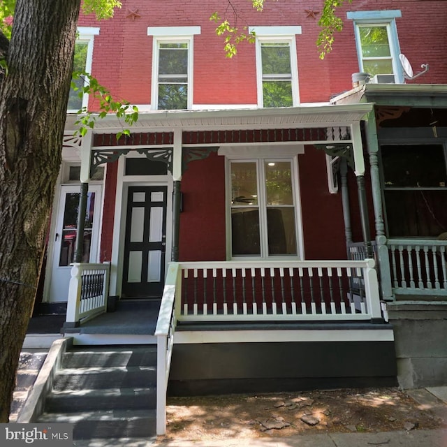 doorway to property with brick siding and covered porch