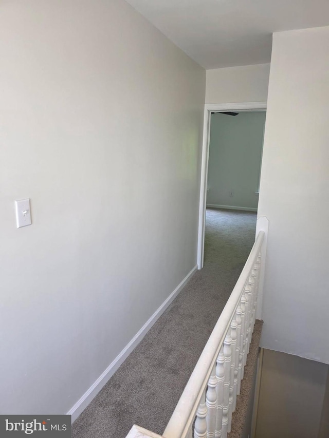 hall featuring baseboards and carpet