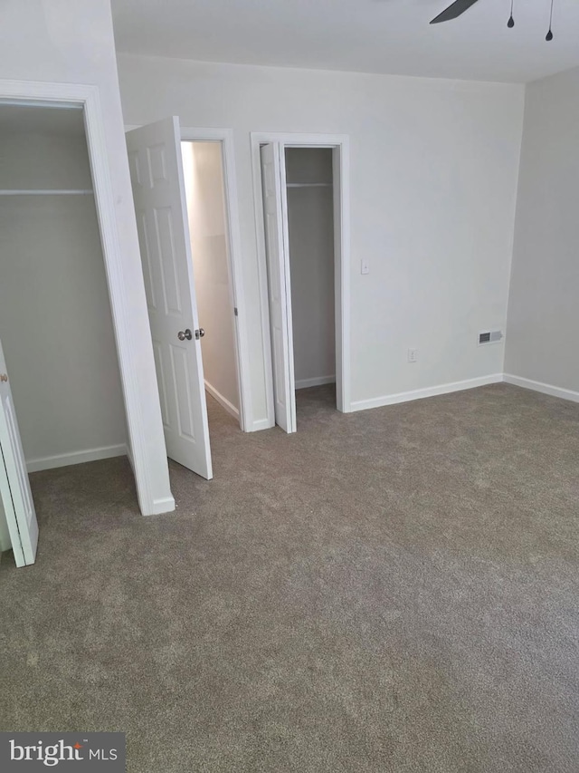 unfurnished bedroom with carpet floors, baseboards, and multiple closets