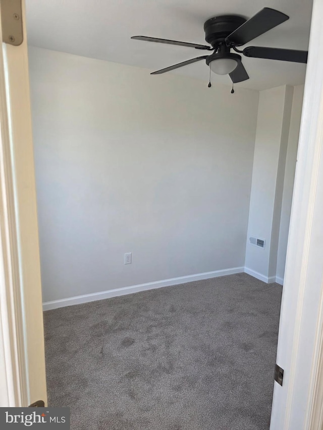 carpeted empty room with ceiling fan, visible vents, and baseboards