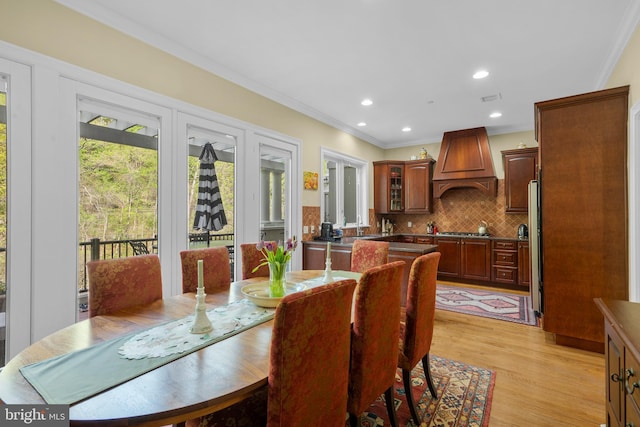 dining space with crown molding, recessed lighting, and light wood-style floors